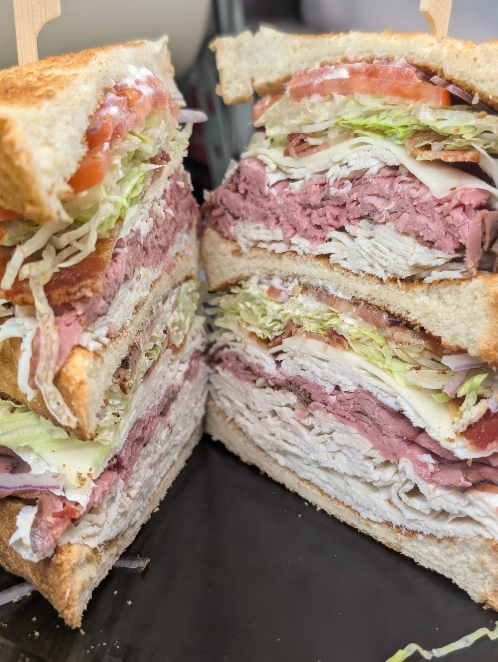 Loaded triple decker club sandwich stacked with turkey, roast beef, bacon and cheese at Sak's Deli